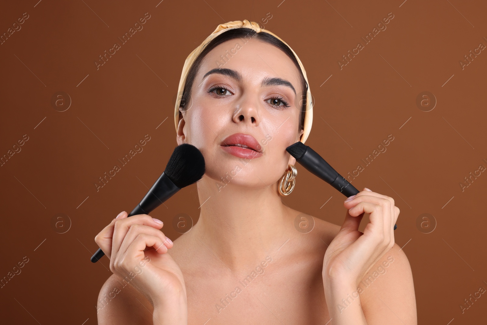 Beautiful woman with makeup brushes on brown background Photo of Beautiful woman with makeup brushes on brown background