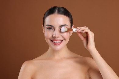 Photo of Beautiful woman with makeup brush on brown background