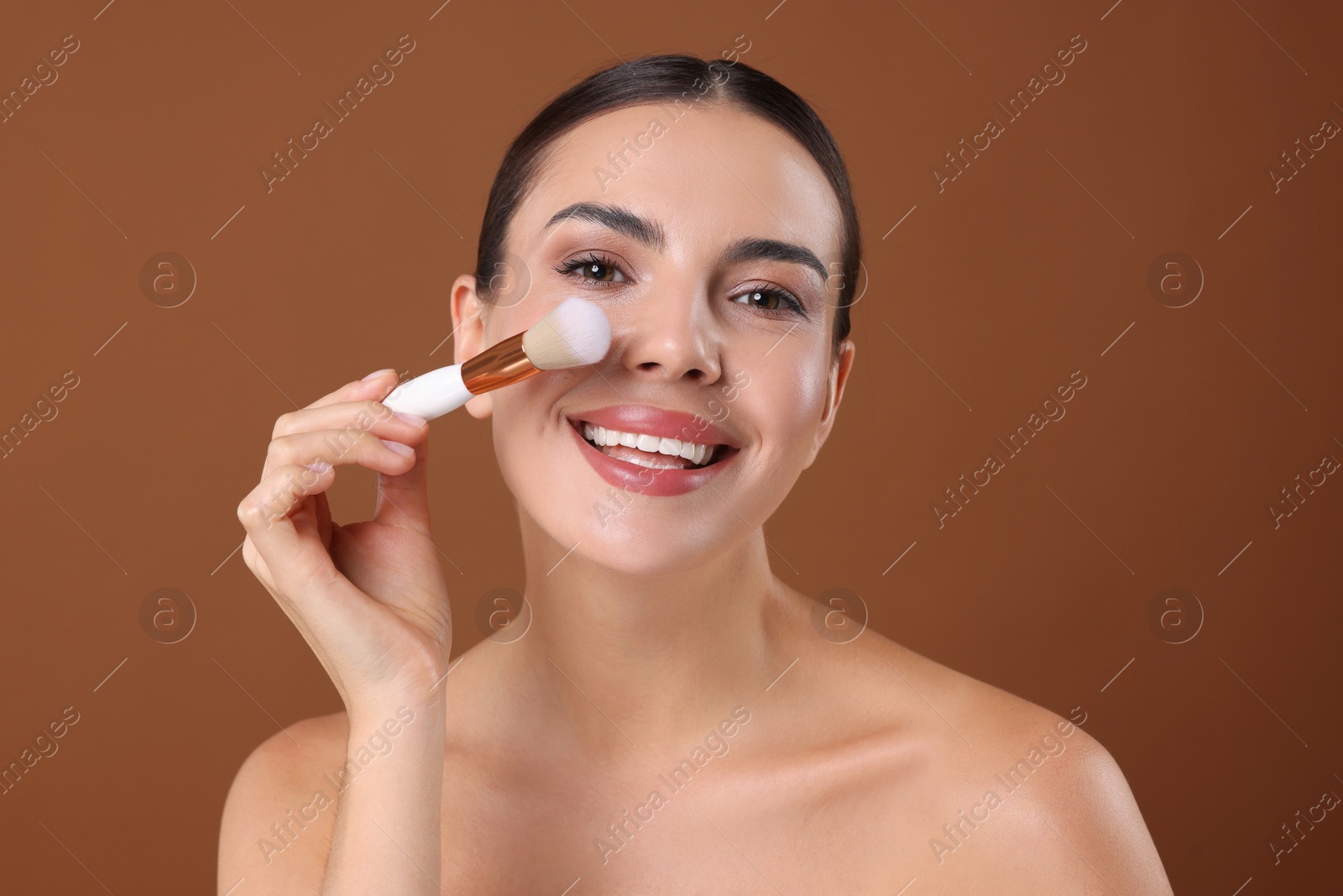 Beautiful woman with makeup brush on brown background Photo of Beautiful woman with makeup brush on brown background