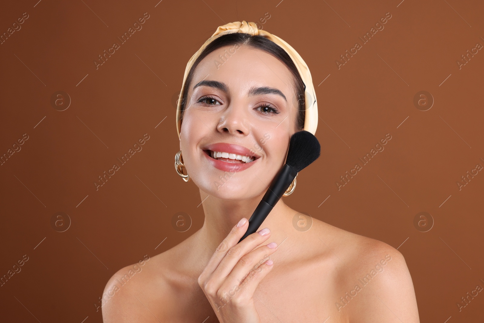 Beautiful woman with makeup brush on brown background Photo of Beautiful woman with makeup brush on brown background