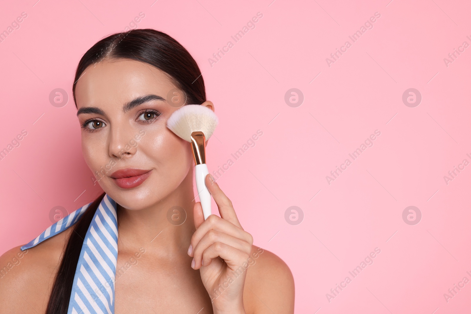 Beautiful woman with makeup brush on pink background, space for text Photo of Beautiful woman with makeup brush on pink background, space for text