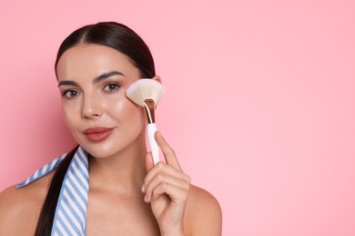Photo of Beautiful woman with makeup brush on pink background, space for text