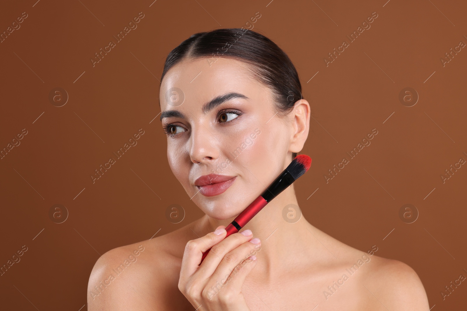 Beautiful woman with makeup brush on brown background Photo of Beautiful woman with makeup brush on brown background