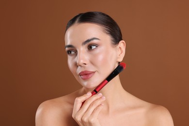 Photo of Beautiful woman with makeup brush on brown background
