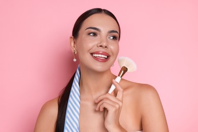Photo of Beautiful woman with makeup brush on pink background