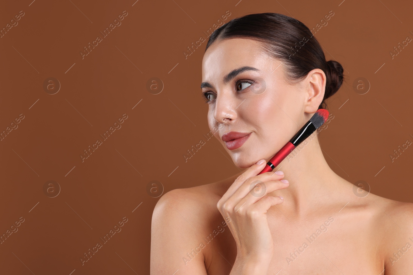 Beautiful woman with makeup brush on brown background, space for text Photo of Beautiful woman with makeup brush on brown background, space for text