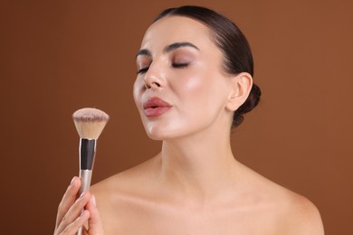 Photo of Beautiful woman with makeup brush on brown background