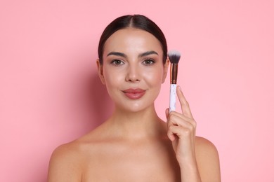 Photo of Beautiful woman with makeup brush on pink background