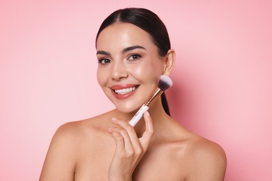 Photo of Beautiful woman with makeup brush on pink background