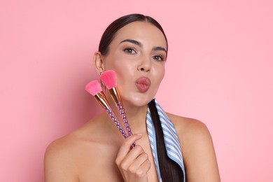 Photo of Beautiful woman with makeup brushes on pink background