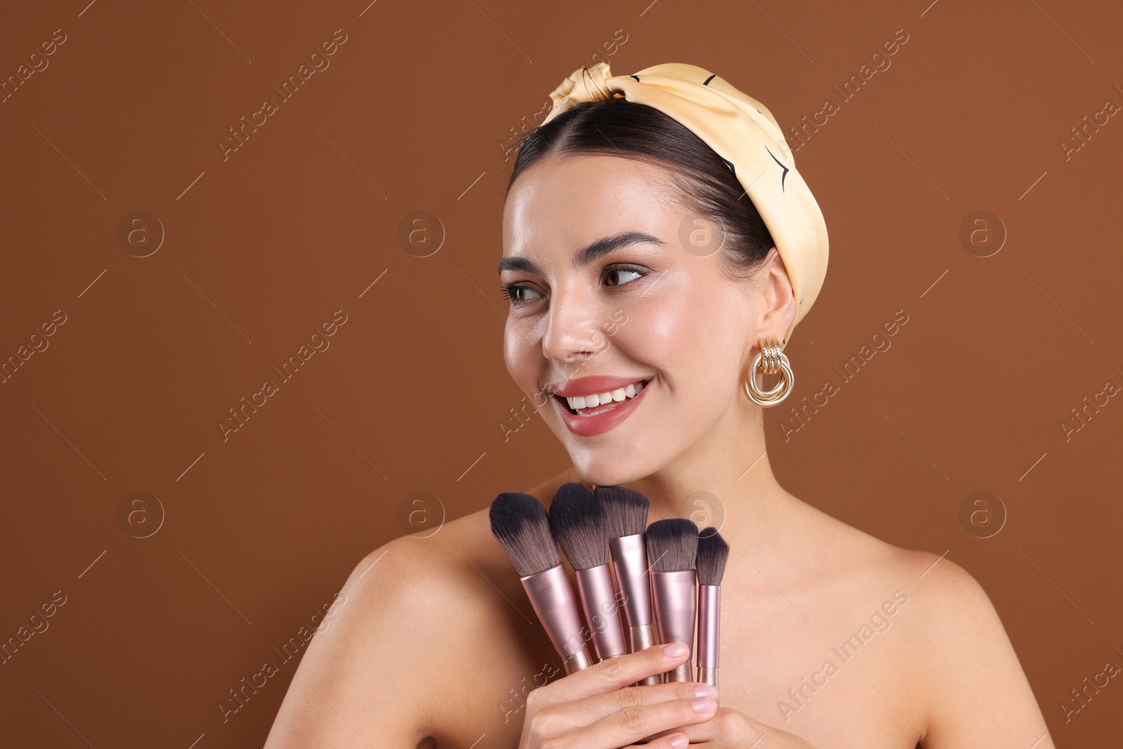 Beautiful woman with makeup brushes on brown background Photo of Beautiful woman with makeup brushes on brown background
