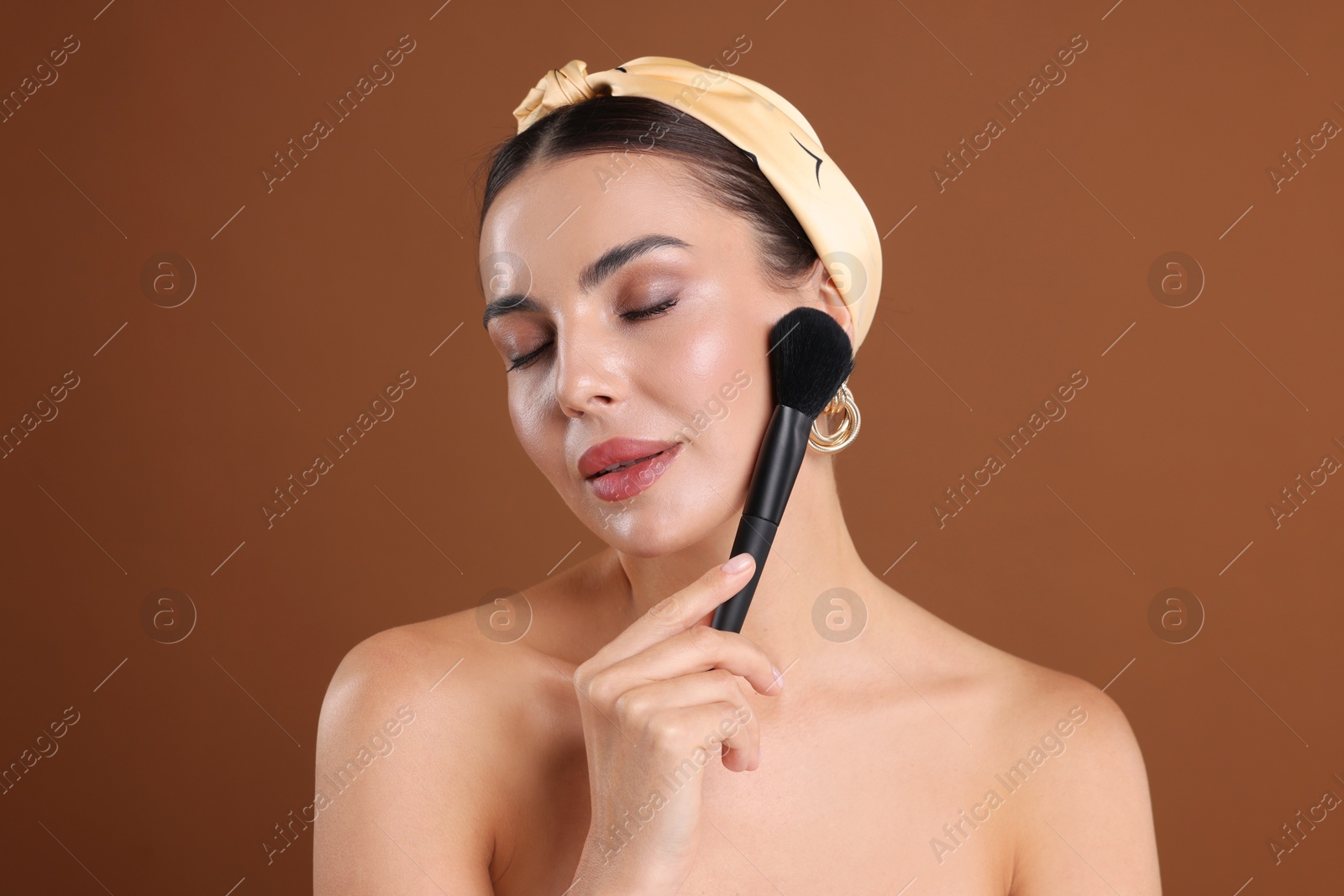 Beautiful woman with makeup brush on brown background Photo of Beautiful woman with makeup brush on brown background