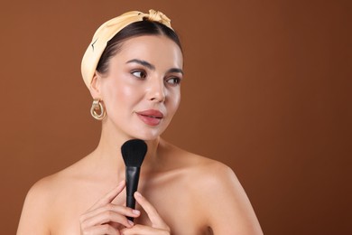 Photo of Beautiful woman with makeup brush on brown background, space for text