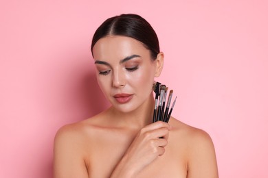 Photo of Beautiful woman with makeup brushes on pink background