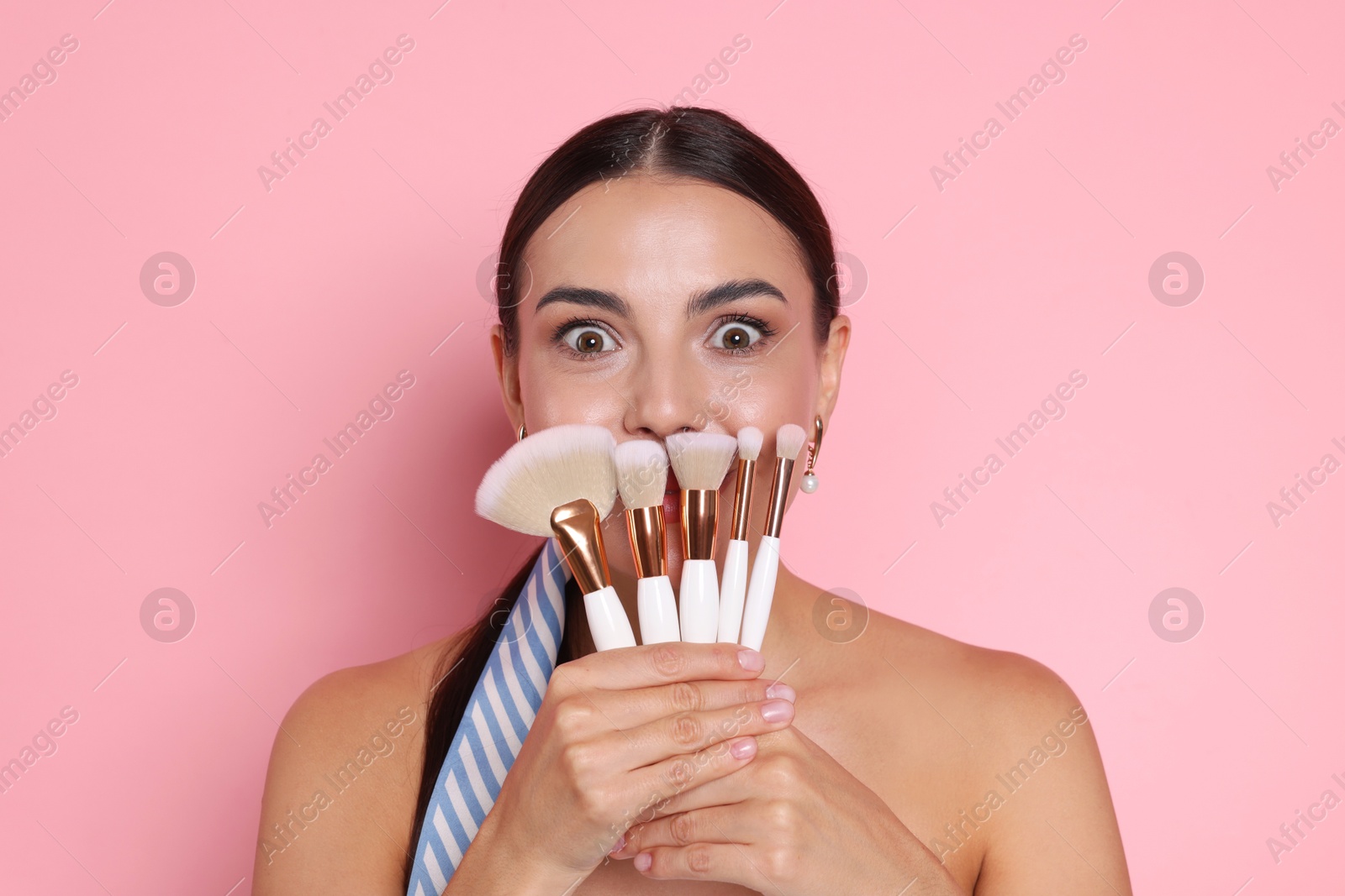 Beautiful woman with makeup brushes on pink background Photo of Beautiful woman with makeup brushes on pink background
