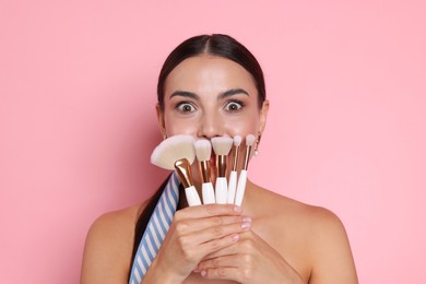 Photo of Beautiful woman with makeup brushes on pink background