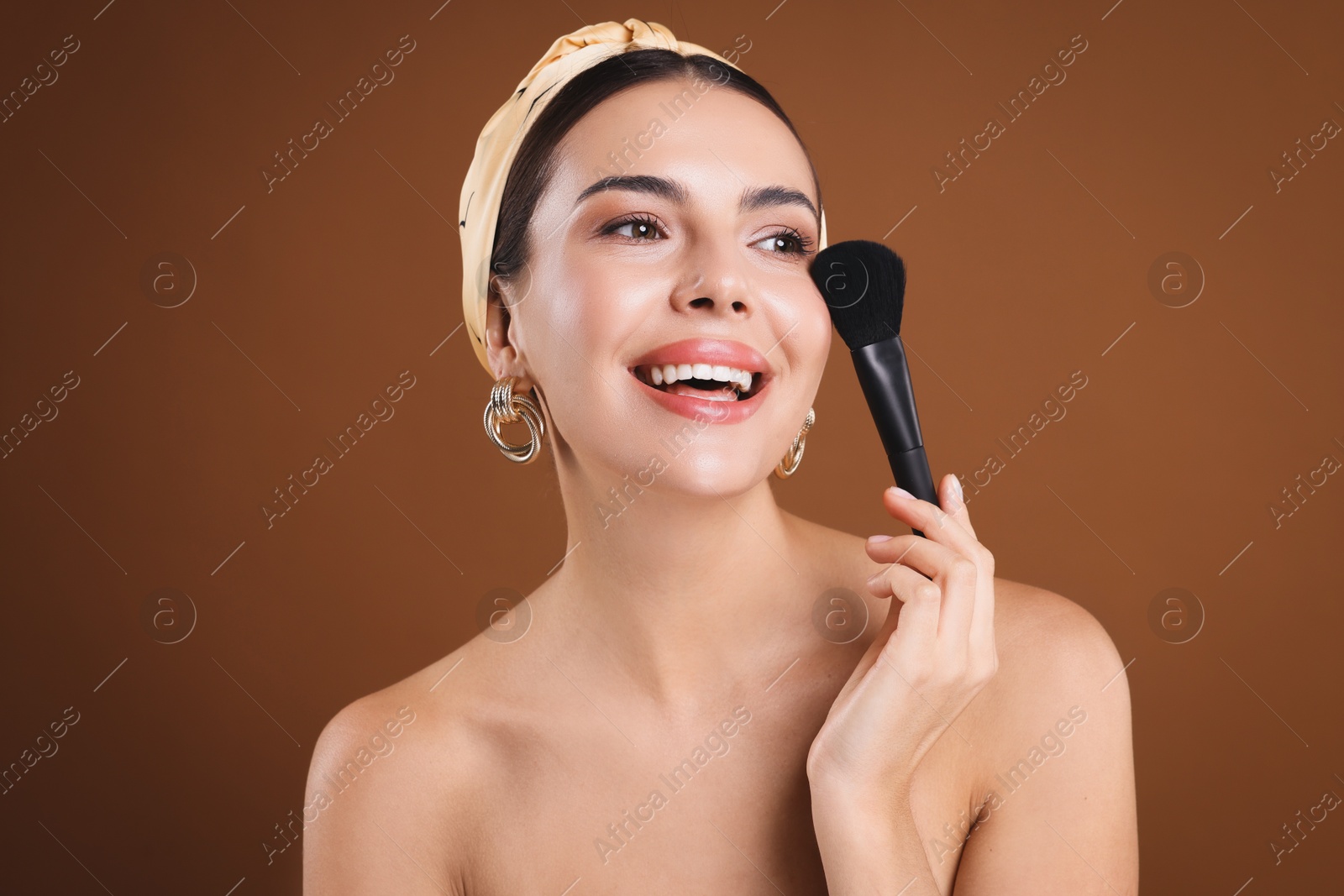 Beautiful woman with makeup brush on brown background Photo of Beautiful woman with makeup brush on brown background