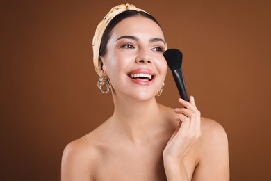 Photo of Beautiful woman with makeup brush on brown background