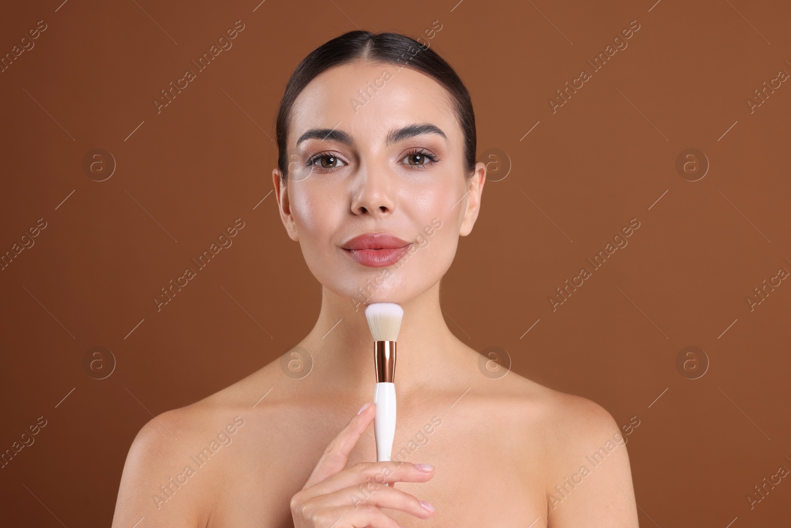 Beautiful woman with makeup brush on brown background Photo of Beautiful woman with makeup brush on brown background