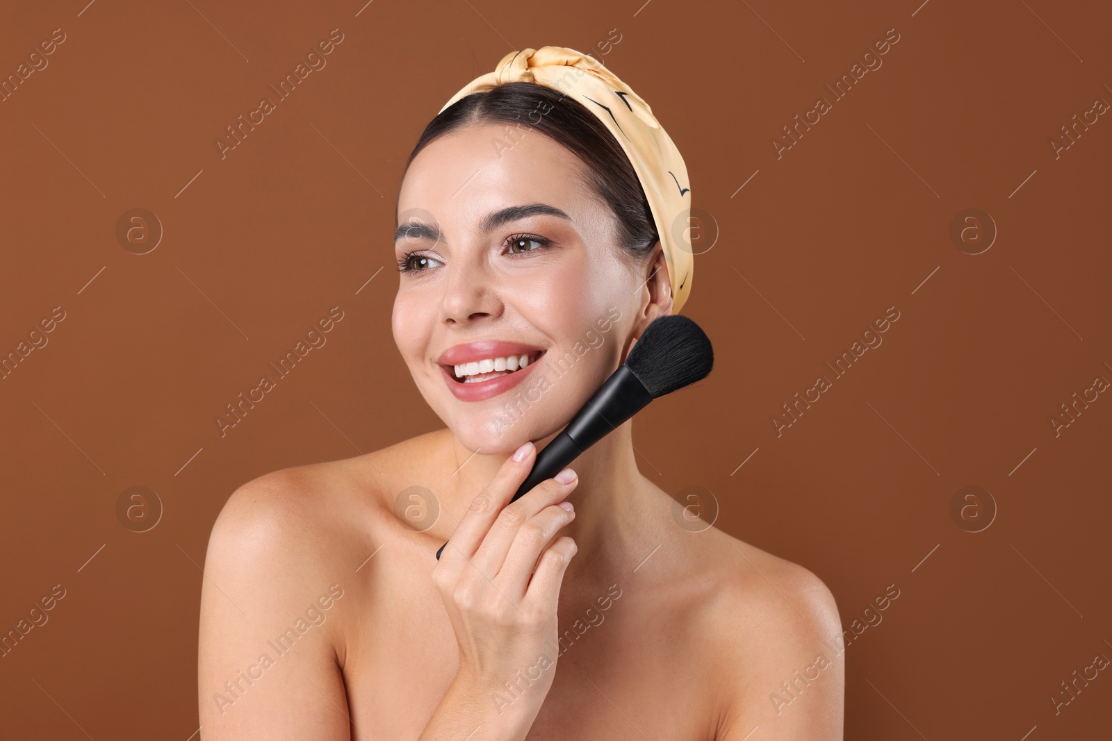 Beautiful woman with makeup brush on brown background Photo of Beautiful woman with makeup brush on brown background