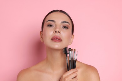 Photo of Beautiful woman with makeup brushes on pink background