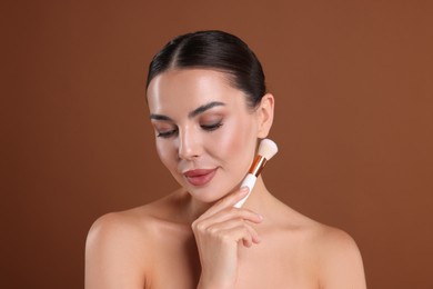 Photo of Beautiful woman with makeup brush on brown background