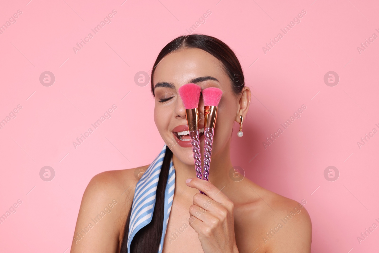 Photo of Beautiful woman with makeup brushes on pink background