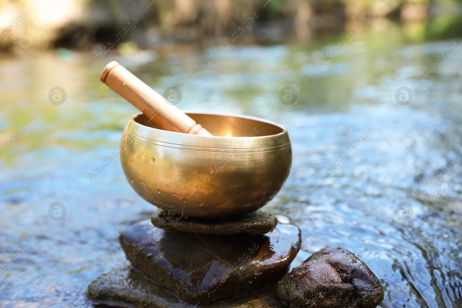 Photo of Tibetan singing bowl with mallet on stone near river
