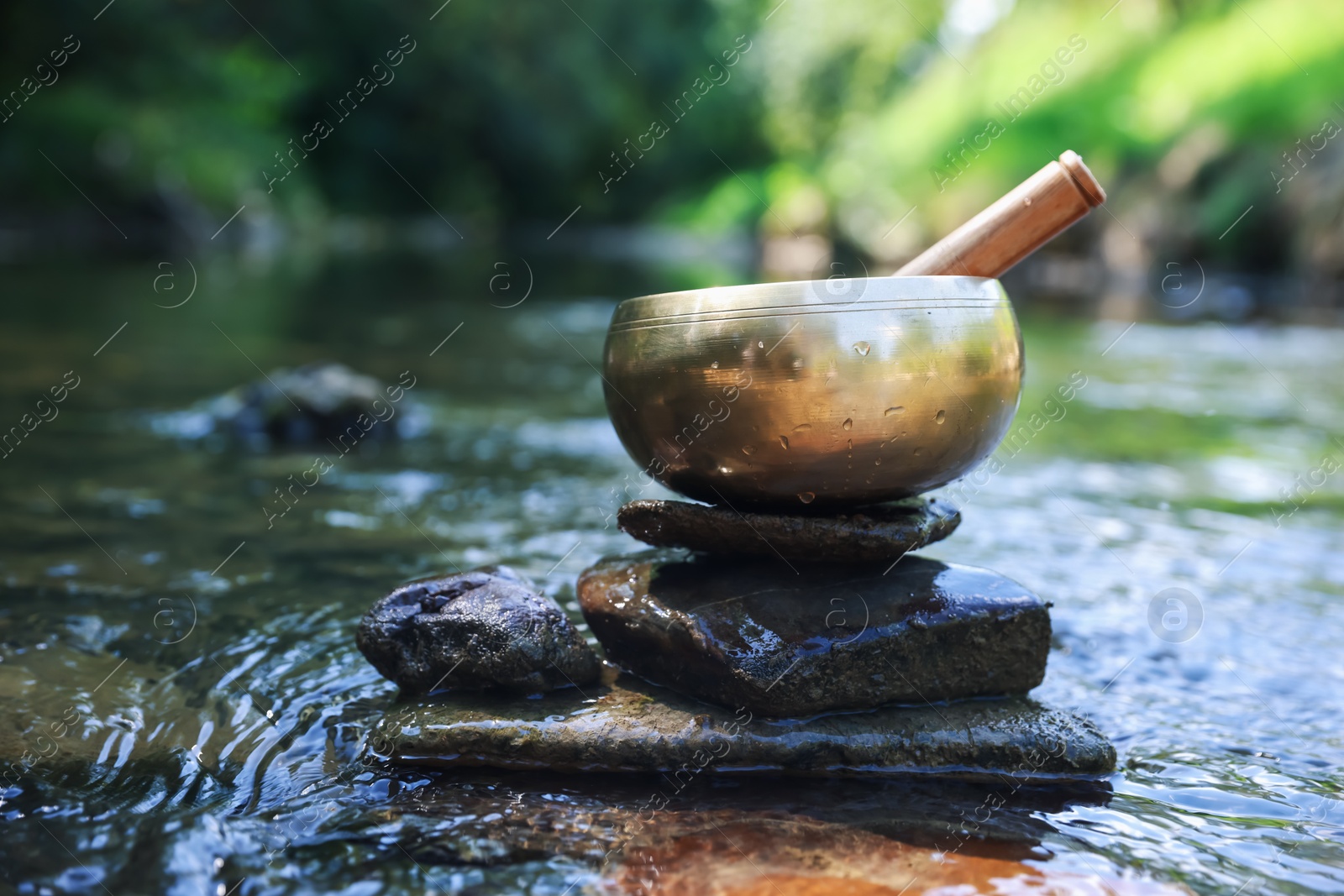 Photo of Tibetan singing bowl with mallet on stone in river