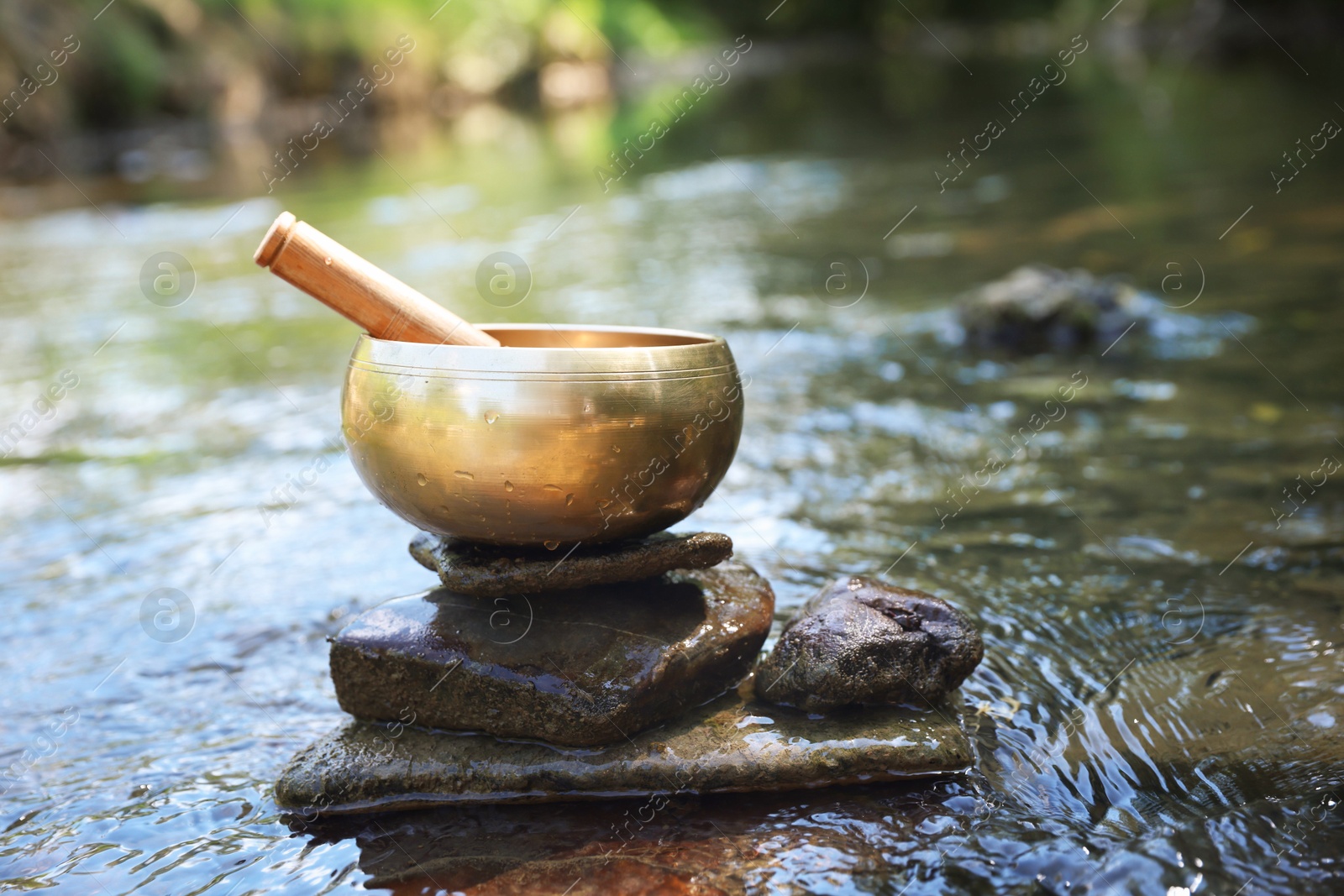 Photo of Tibetan singing bowl with mallet on stone in river