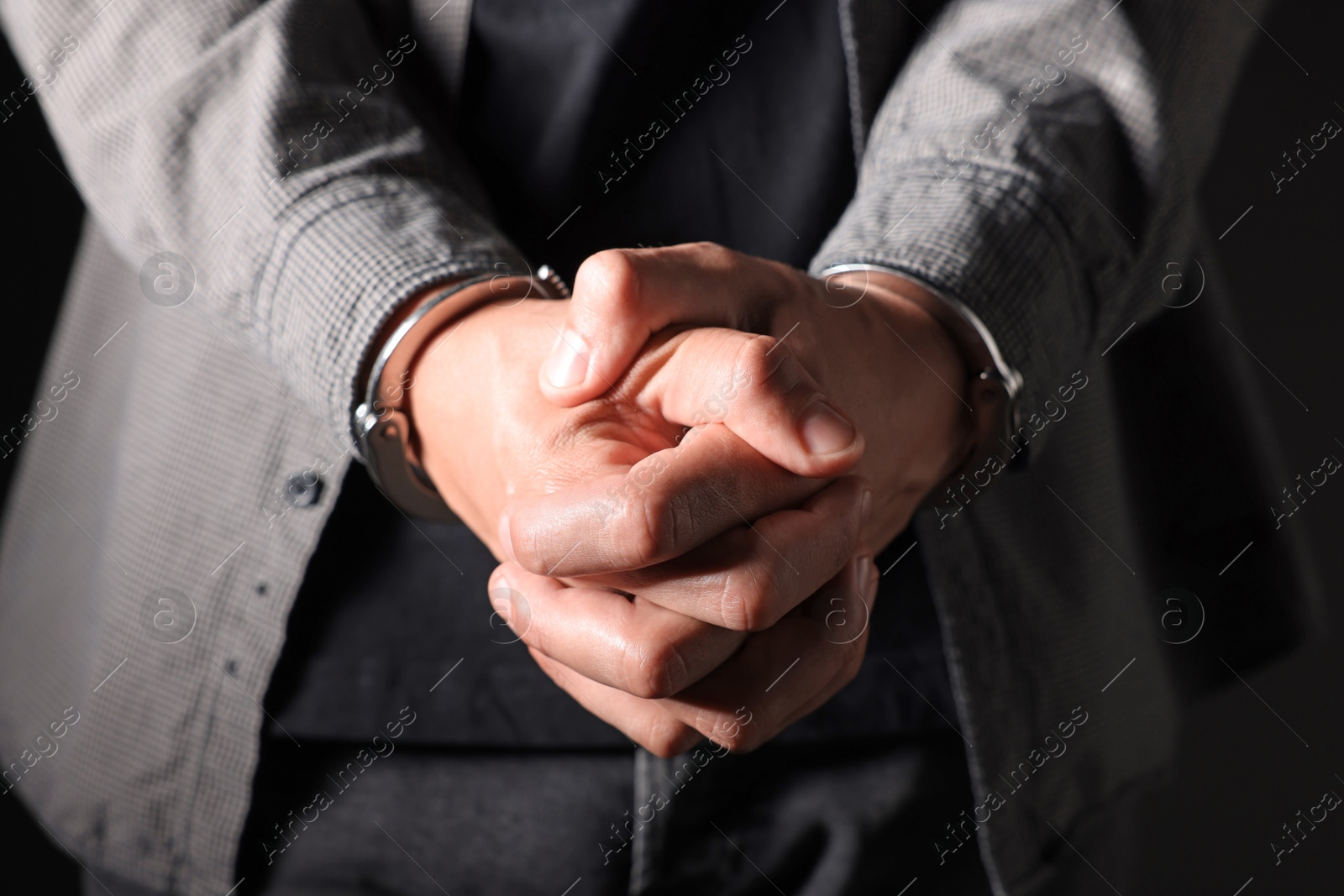 Photo of Man in metal handcuffs on black background, closeup