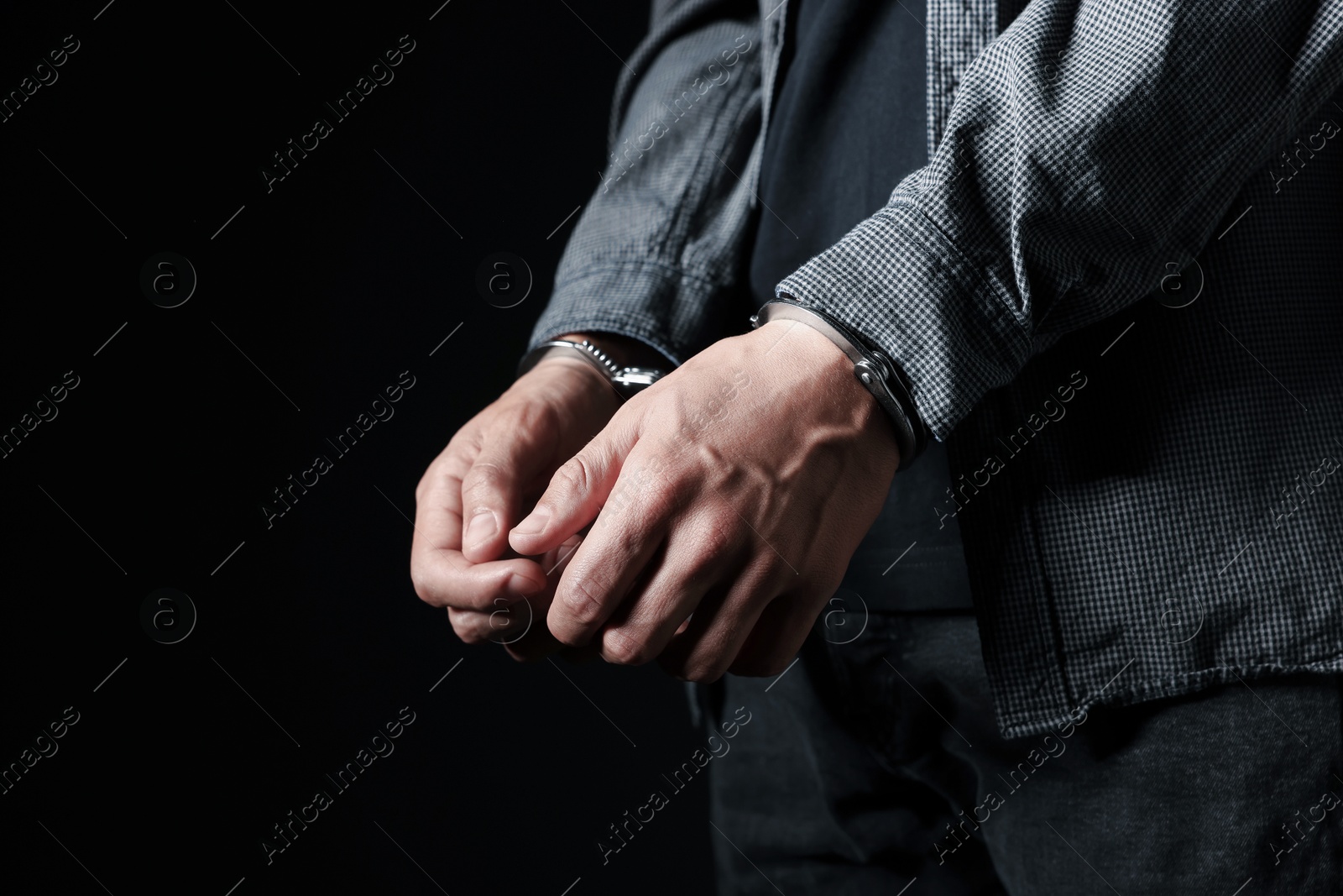 Man in metal handcuffs on black background, closeup. Space for text Photo of Man in metal handcuffs on black background, closeup. Space for text
