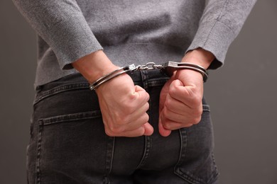 Photo of Man in metal handcuffs on grey background, closeup