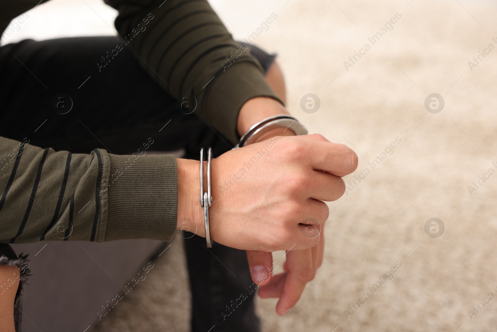 Photo of Man in metal handcuffs on blurred background, closeup. Space for text