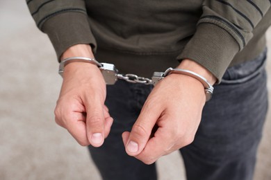 Photo of Man in metal handcuffs on blurred background, closeup