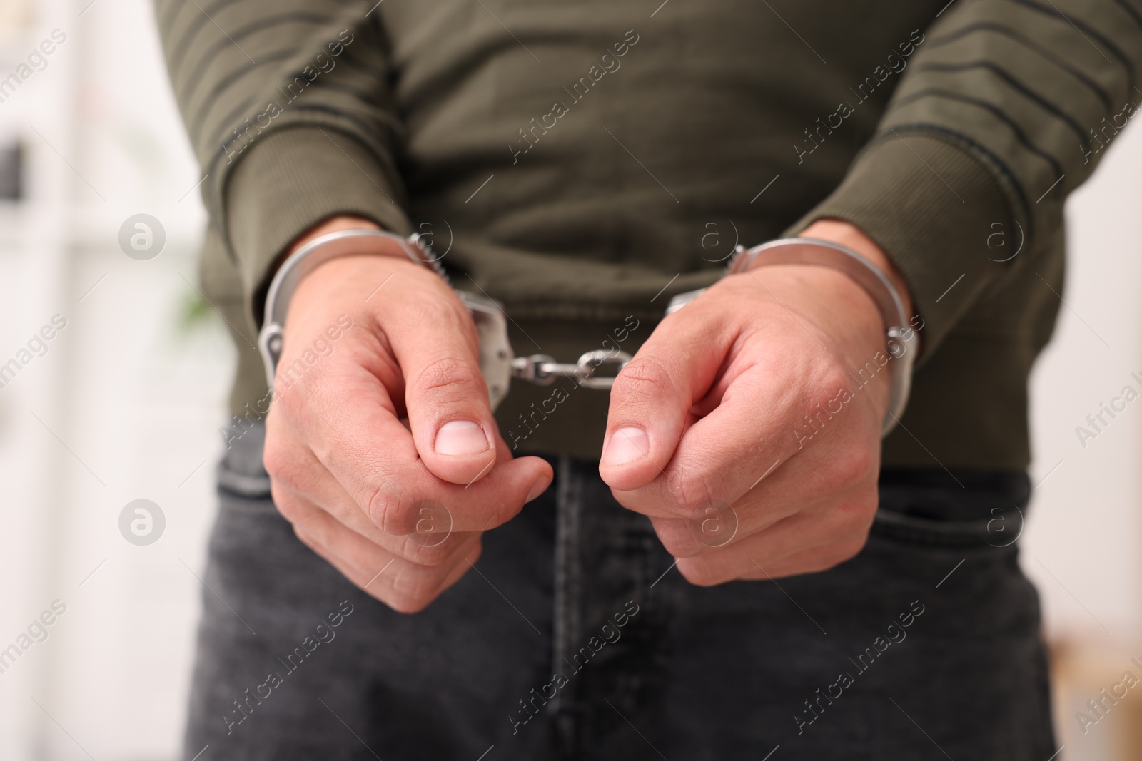 Photo of Man in metal handcuffs on blurred background, closeup