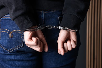 Photo of Woman in metal handcuffs indoors, back view