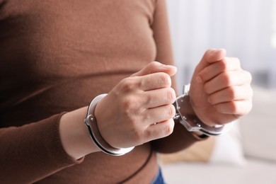 Photo of Woman in metal handcuffs indoors, closeup view