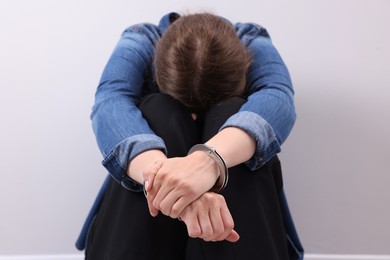 Photo of Woman in metal handcuffs near light grey wall