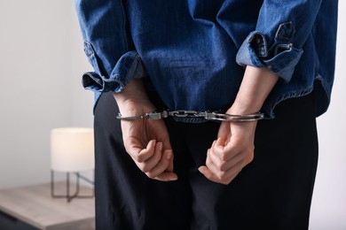 Photo of Woman in metal handcuffs indoors, back view