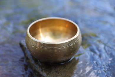 Photo of Tibetan singing bowl on stone in river, closeup