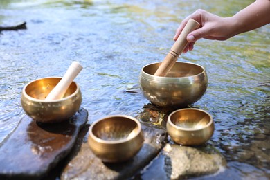 Photo of Woman with singing bowls by river, closeup