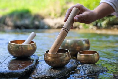 Photo of Woman with singing bowls by river, closeup