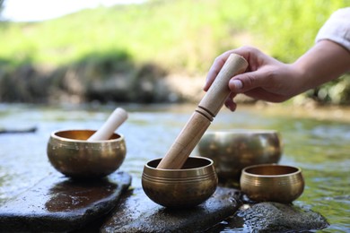 Photo of Woman with singing bowls by river, closeup