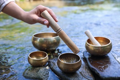 Photo of Woman with singing bowls by river, closeup