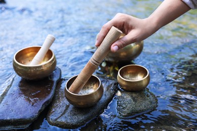 Photo of Woman with singing bowls by river, closeup