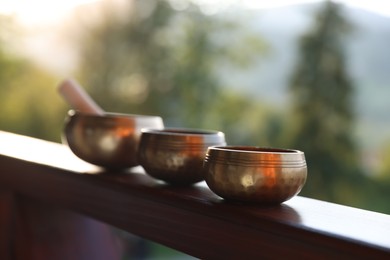 Photo of Tibetan singing bowls with mallet on handrail outdoors, closeup