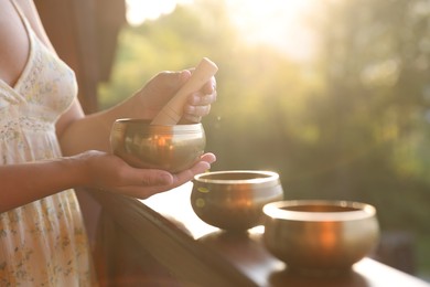 Photo of Woman with singing bowls outdoors on sunny day, closeup