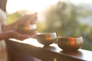 Photo of Woman with singing bowls outdoors on sunny day, selective focus
