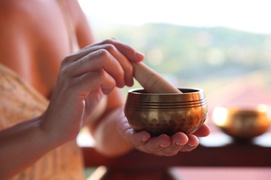 Photo of Woman with singing bowl outdoors, closeup view